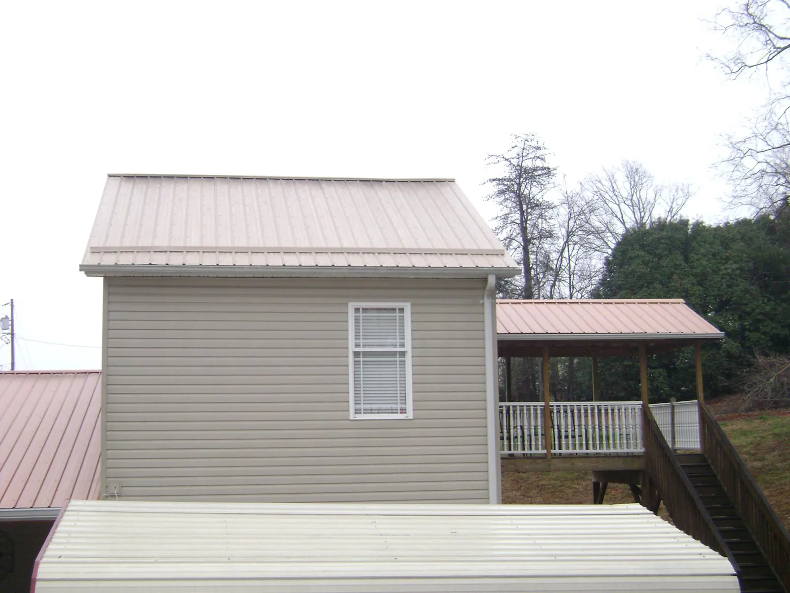 Tan metal roofs on a two story addition and attached porch, from a Roof Replacement job in Climax